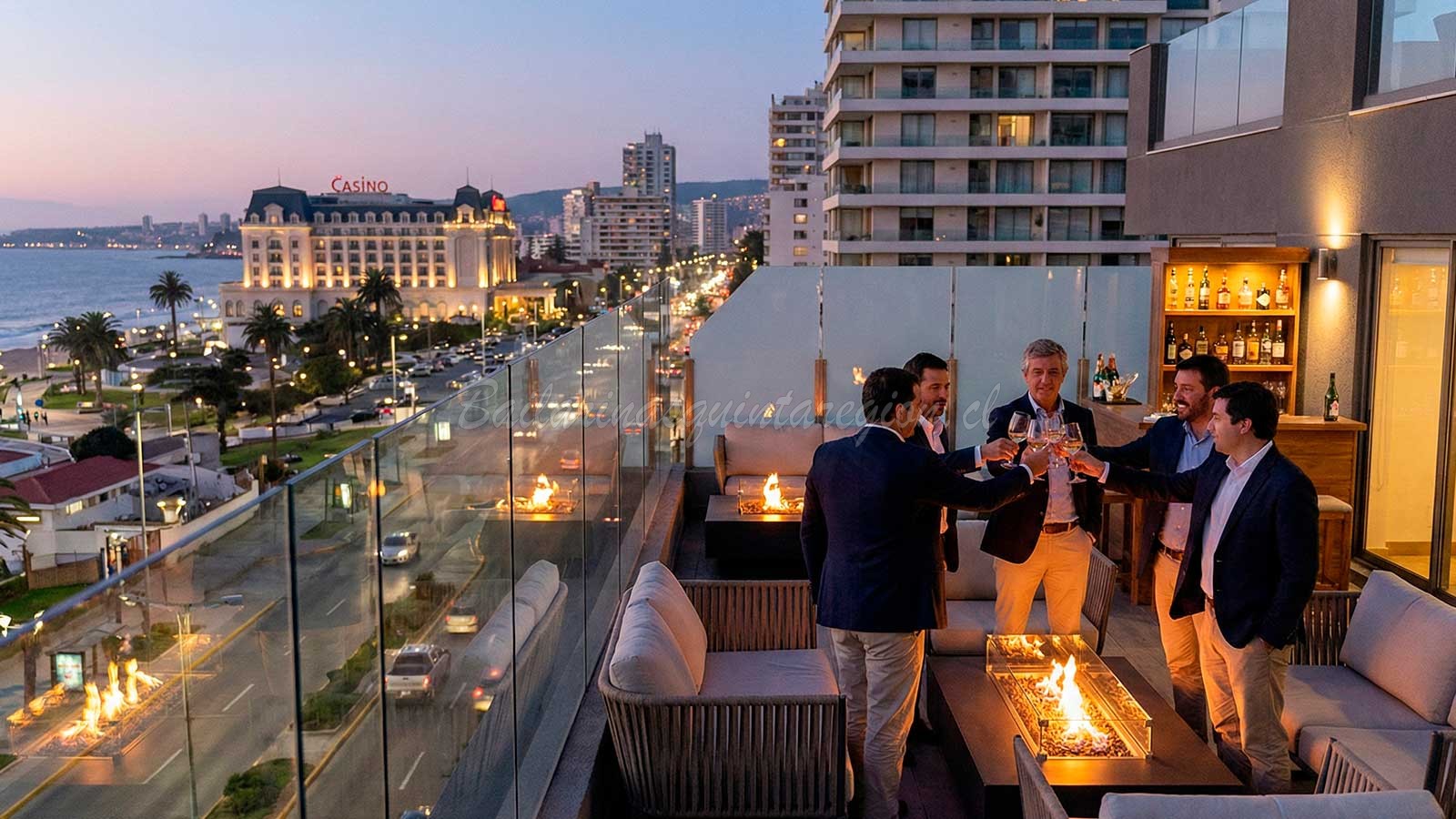 Grupo de amigos celebrando despedida de soltero en terraza privada con vista al Casino de Viña del Mar y la costa al atardecer
