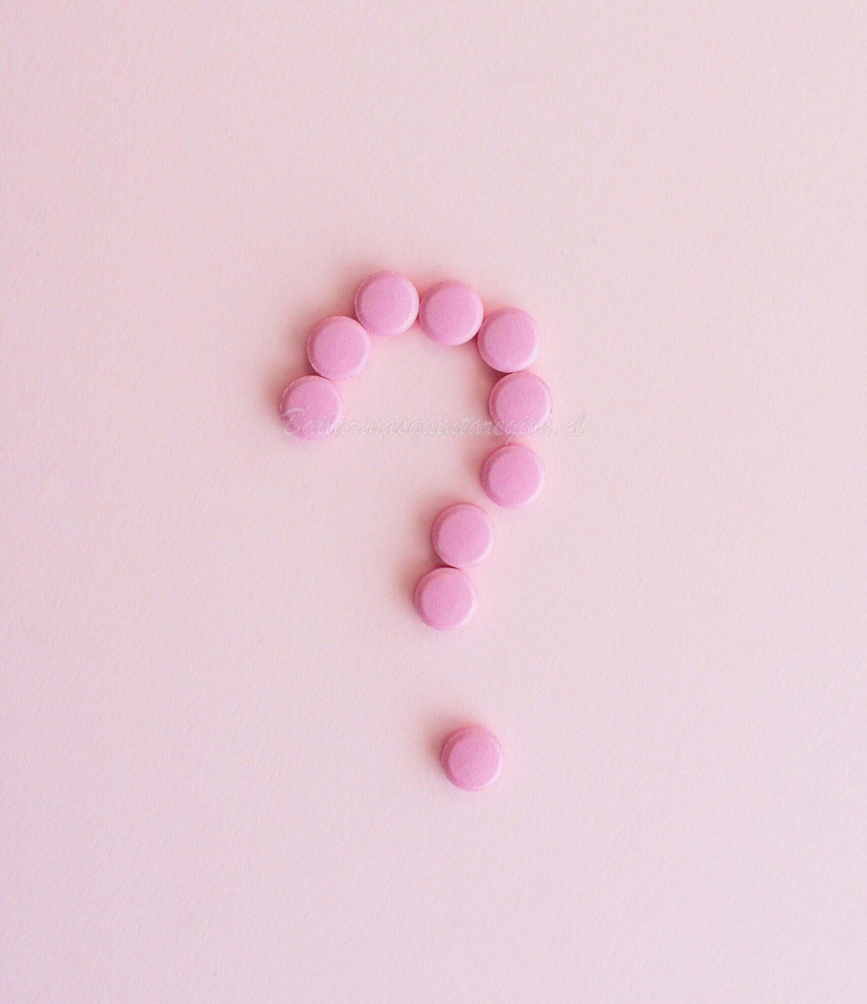 Pink pills forming a question mark on a pastel surface, symbolizing uncertainty in health decisions.